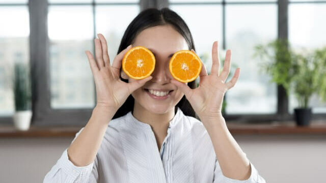 Junge Frau mit halbierten Orangen vor den Augen