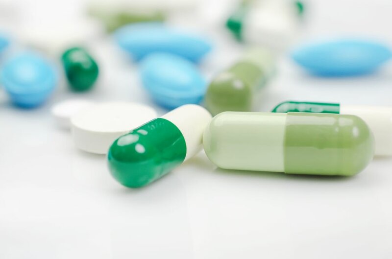 Medikamente in Form von grünen Kapseln und blauen Pillen