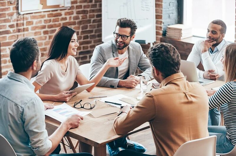 Junge Menschen sitzen lachend in einem Teammeeting