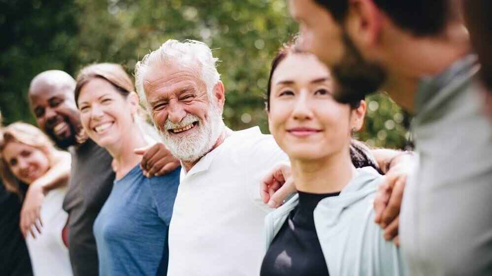 Diverse Menschen unterschiedlichen Alters in einer Reihe, lachend
