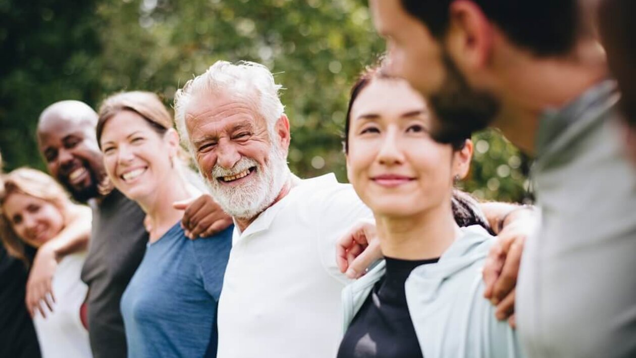 Diverse Menschen unterschiedlichen Alters in einer Reihe, lachend