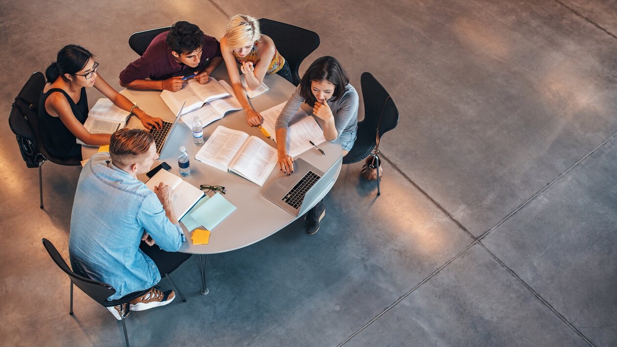 Gruppe Studierende über ihren Büchern am runden Tisch