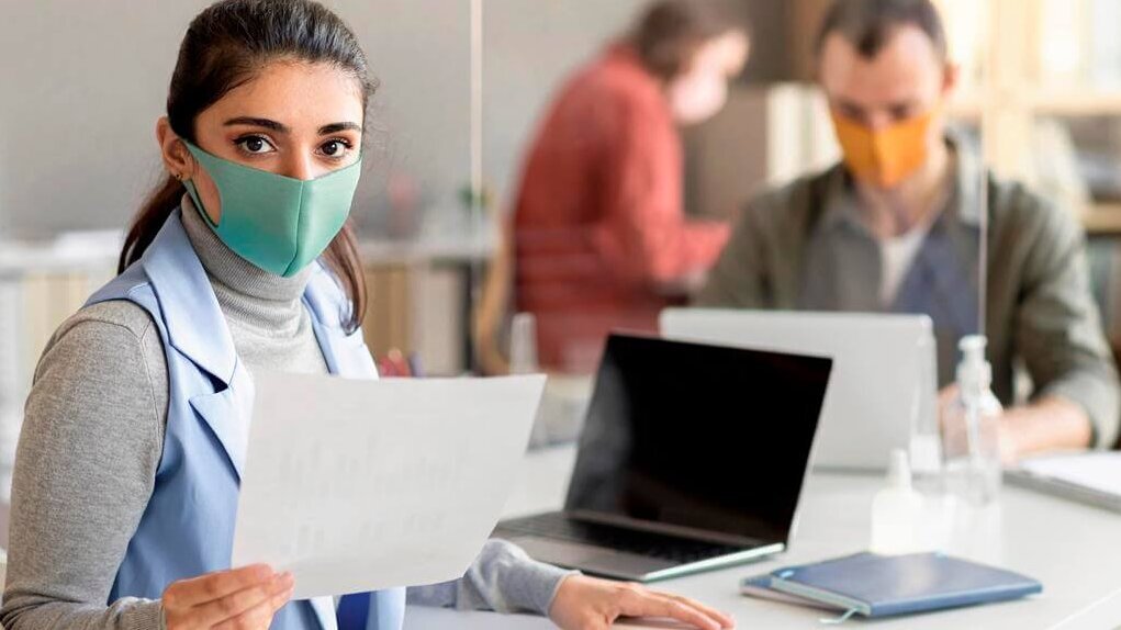 Eine medizinische Assistentin mit Mundschutz in einer Anmeldesituation in einer Arztpraxis mit einem Mundschutz