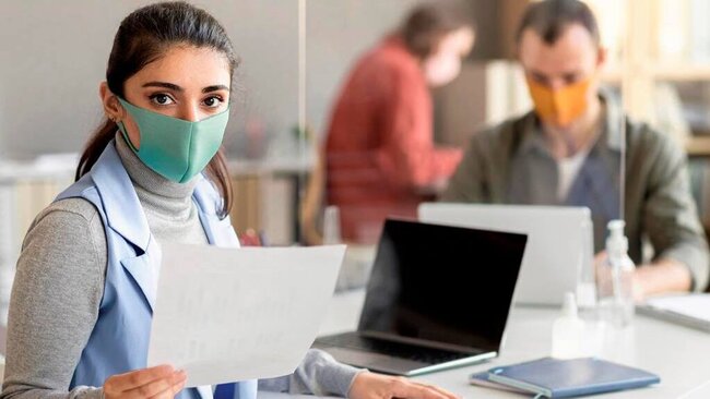 Eine medizinische Assistentin mit Mundschutz in einer Anmeldesituation in einer Arztpraxis mit einem Mundschutz