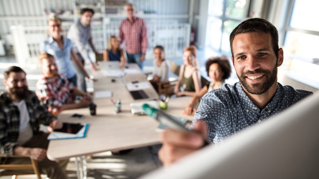 Junger Mann im Meeting schreibt an Whiteboard