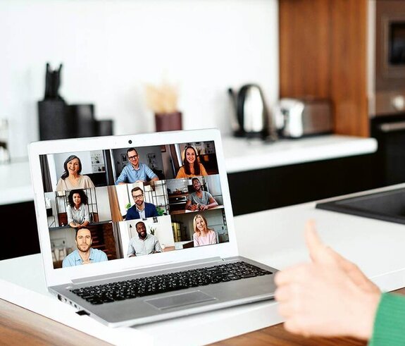 Eine Frau am Computer, die online mit anderen zusammen arbeitet