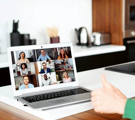 Eine Frau am Computer, die online mit anderen zusammen arbeitet