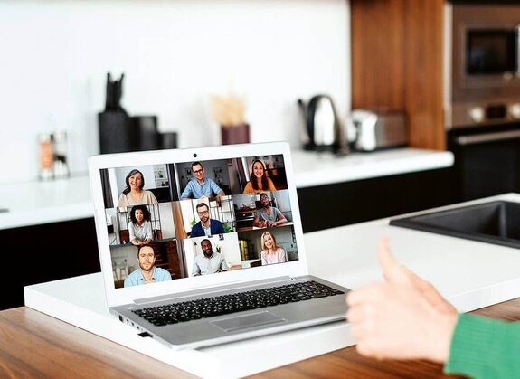 Eine Frau am Computer, die online mit anderen zusammen arbeitet