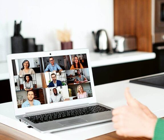 Eine Frau am Computer, die online mit anderen zusammen arbeitet