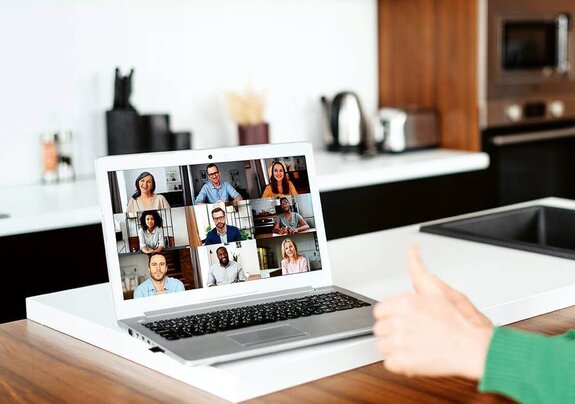 Eine Frau am Computer, die online mit anderen zusammen arbeitet