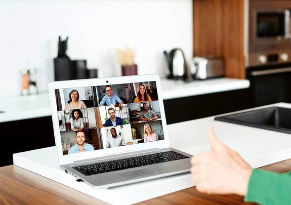 Eine Frau am Computer, die online mit anderen zusammen arbeitet