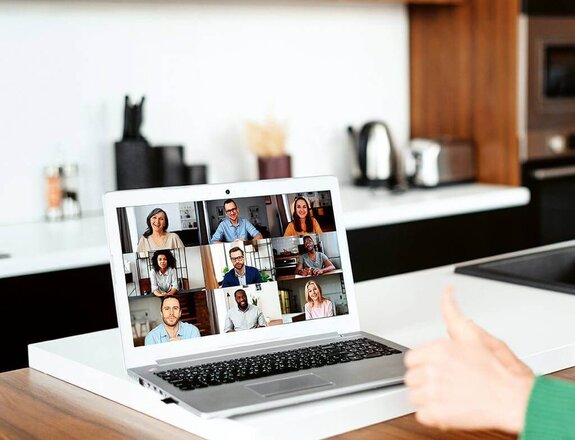 Eine Frau am Computer, die online mit anderen zusammen arbeitet