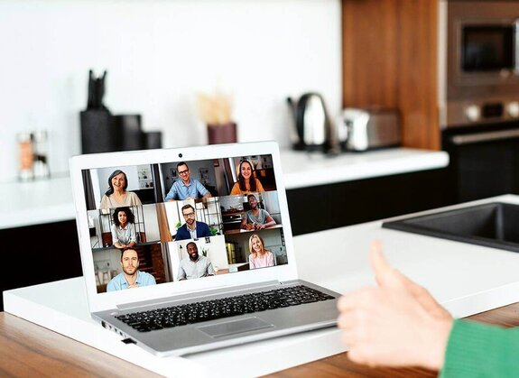 Eine Frau am Computer, die online mit anderen zusammen arbeitet