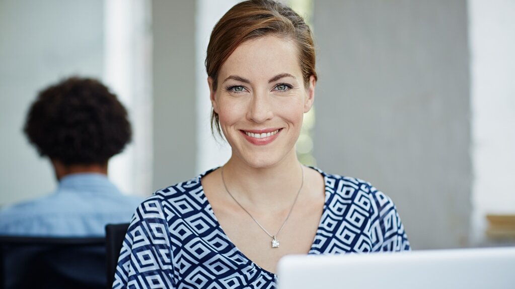 Portrait sympatisch lächelnder Frau vor Laptop