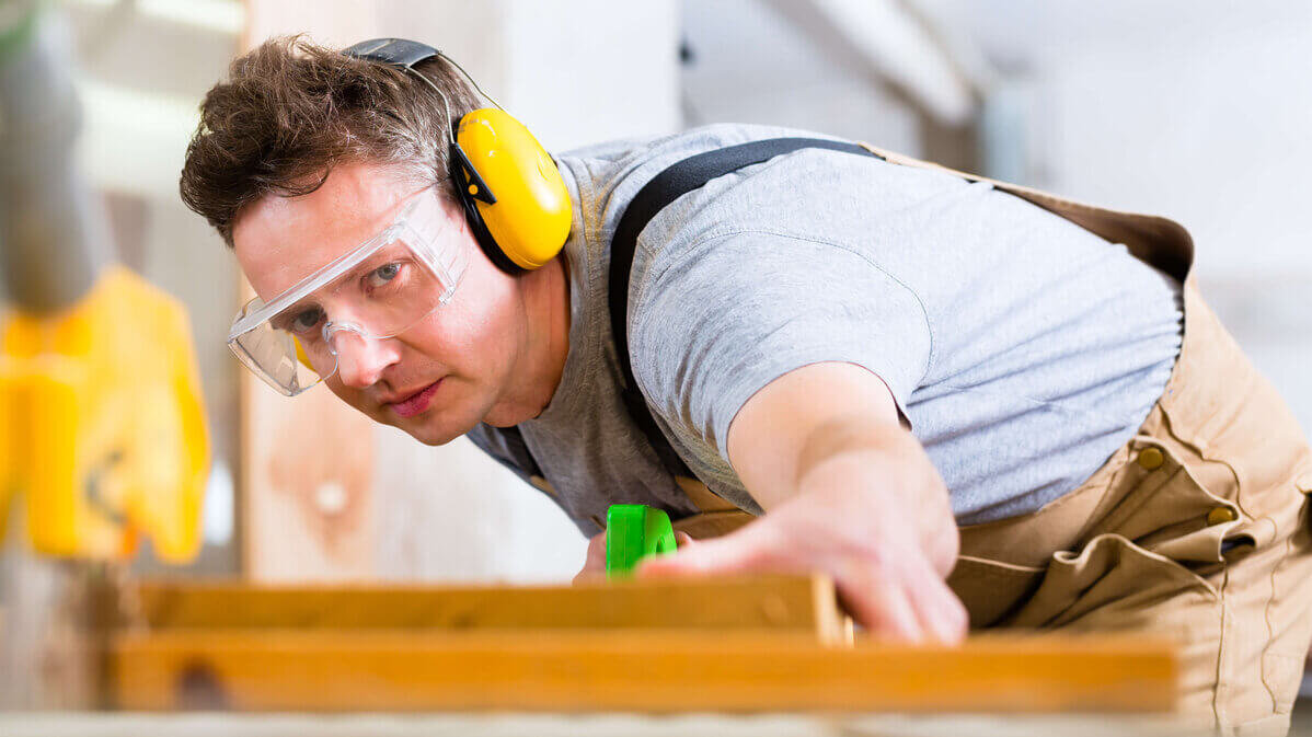 Mann bei der Arbeit mit Gehörschutz und Schutzbrille  