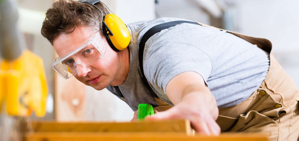 Mann bei der Arbeit mit Gehörschutz und Schutzbrille  