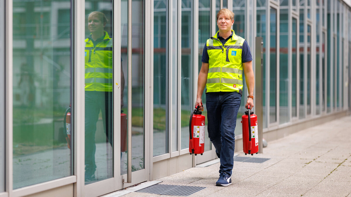 Sebastian Steder, Sicherheitsexperte der ias bei der Vorbereitung auf eine Brandschutzübung mit zwei Feuerlöschern