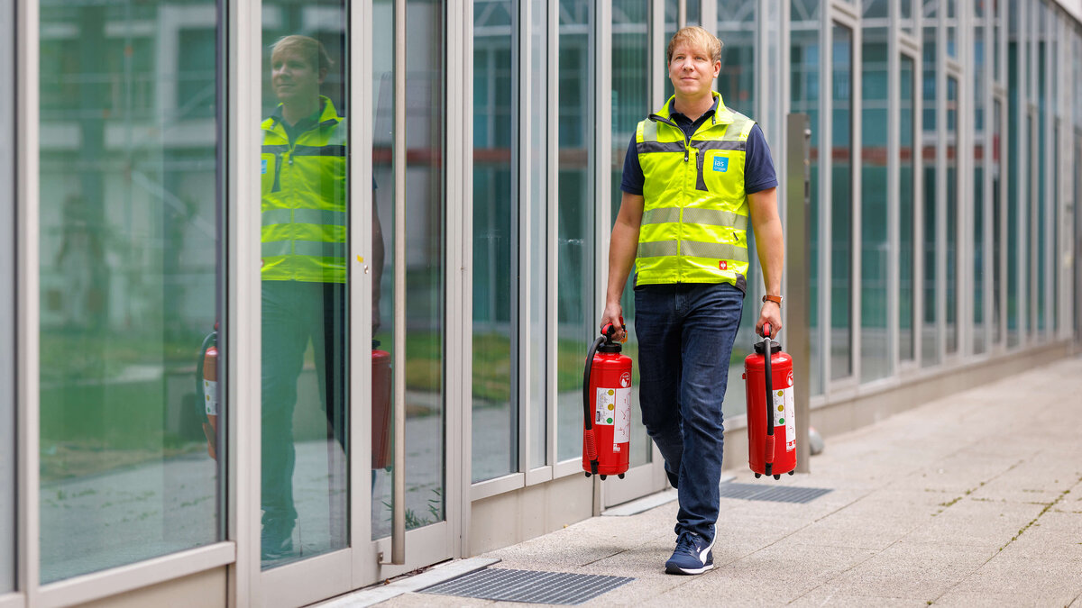 Sebastian Steder, Sicherheitsexperte der ias bei der Vorbereitung auf eine Brandschutzübung mit zwei Feuerlöschern