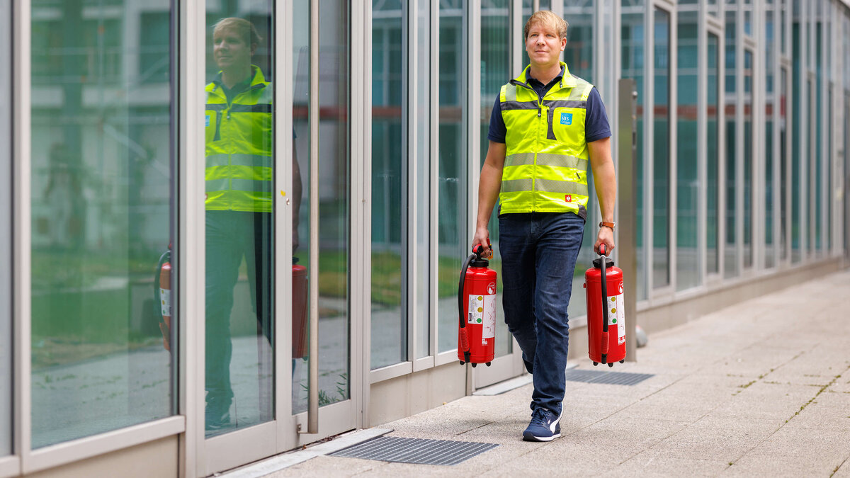 Sebastian Steder, Sicherheitsexperte der ias bei der Vorbereitung auf eine Brandschutzübung mit zwei Feuerlöschern