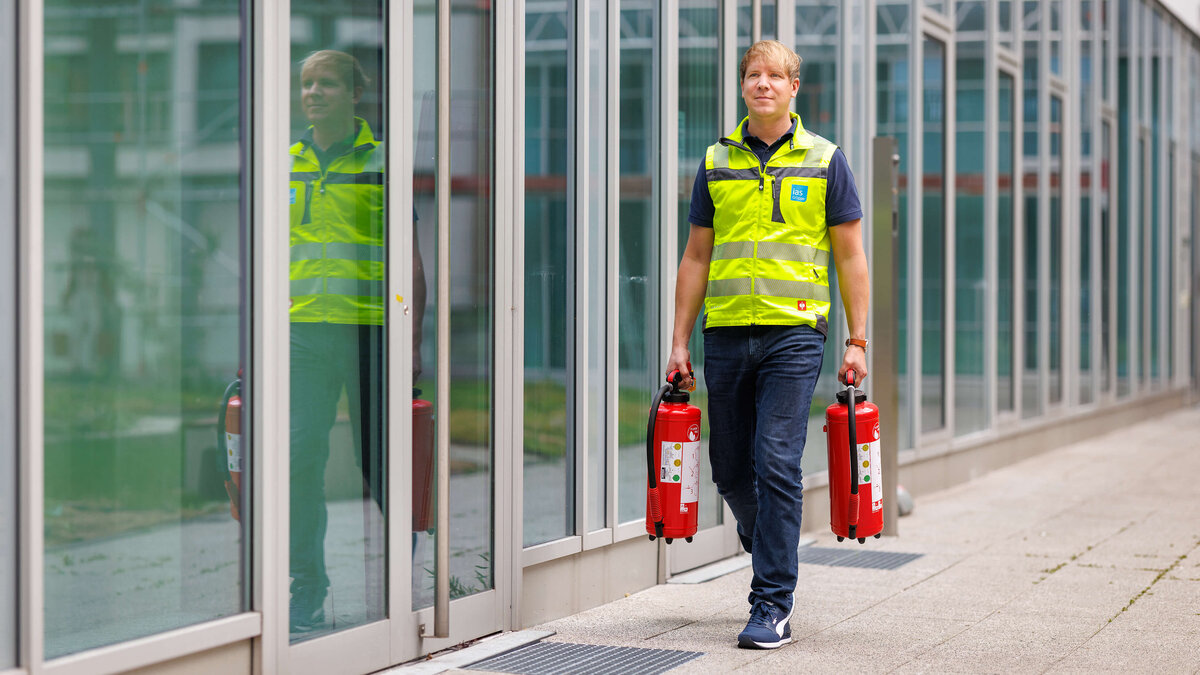Sebastian Steder, Sicherheitsexperte der ias bei der Vorbereitung auf eine Brandschutzübung mit zwei Feuerlöschern