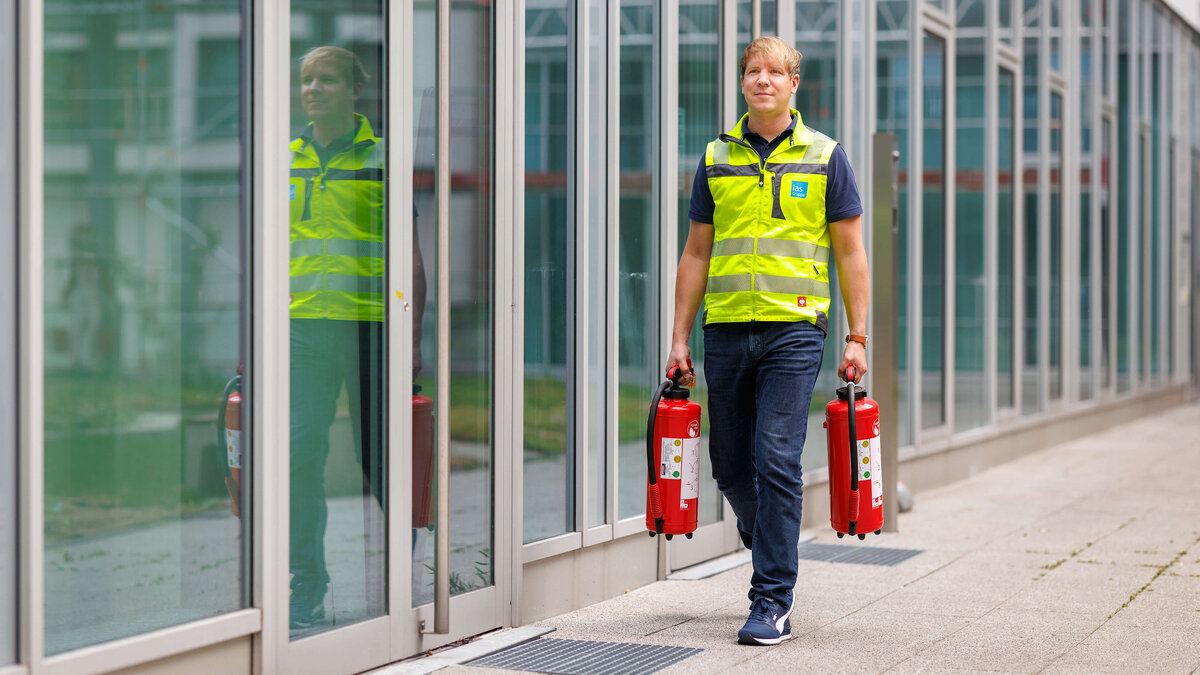 Sebastian Steder, Sicherheitsexperte der ias bei der Vorbereitung auf eine Brandschutzübung mit zwei Feuerlöschern