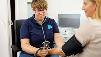 Arbeitsmedizinische Assistenz Jennifer Smarz misst Blutdruck bei einer arbeitsmedizinischen Untersuchung