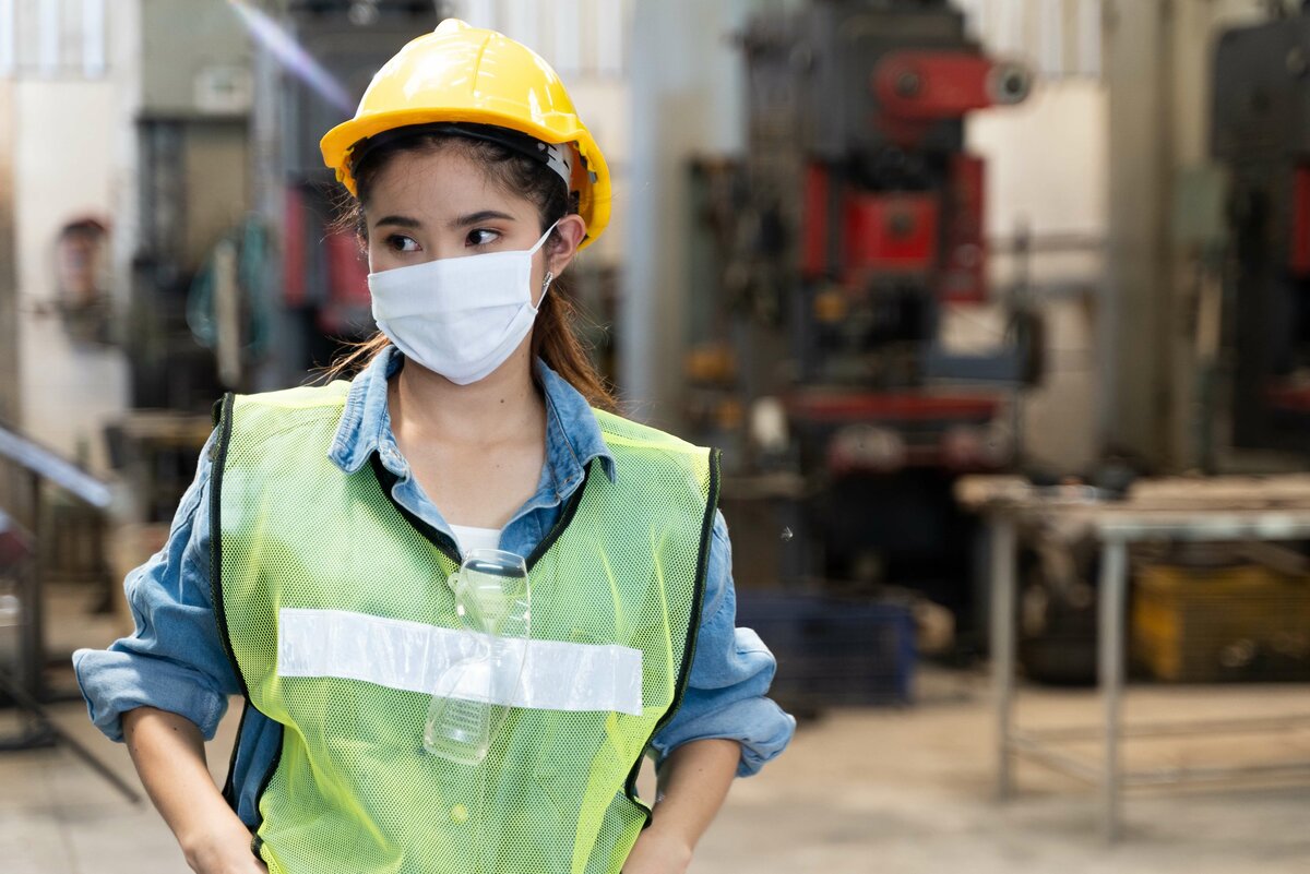 Frau in der Produktion mit Mundschutz während der Corona-Pandemie