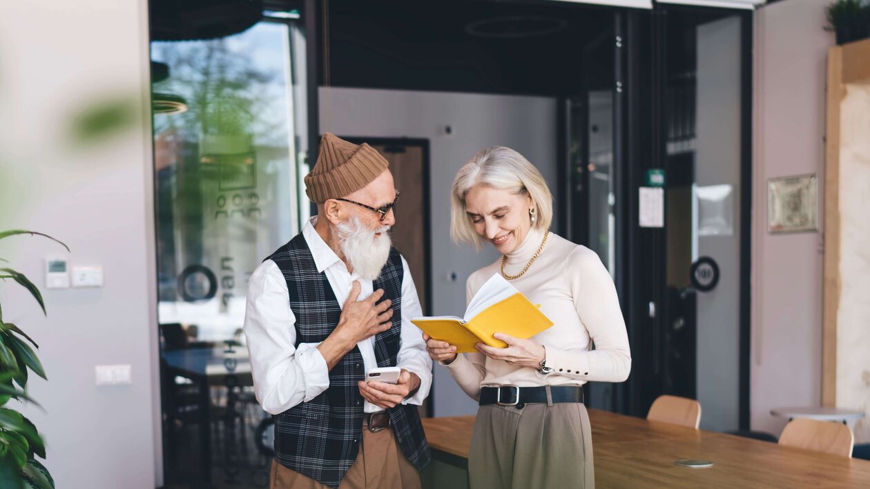 Ein modernes älteres Paar steht in einem individuell eingerichtetem Wohnumfeld