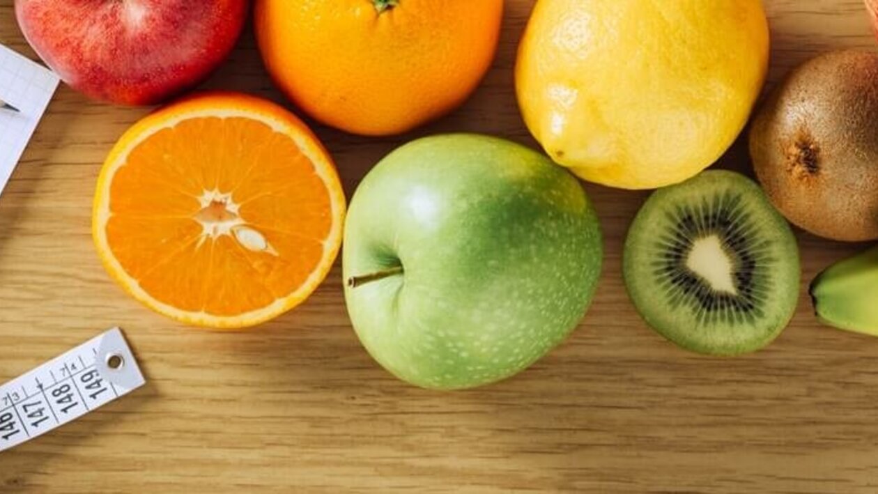 Hanteln, Obst, Wasser, Waage und Tablet auf dem Boden