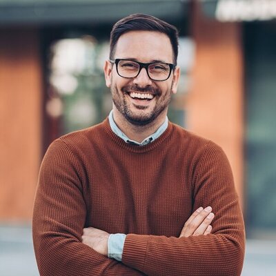 lachender junger Mann mit verschränkten Armen