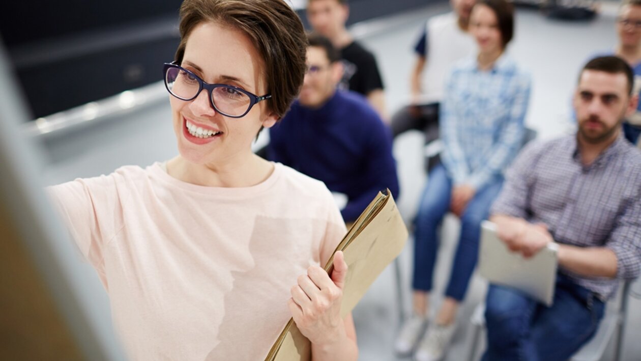 junge Frau mit Brille schreibt am Flipchart