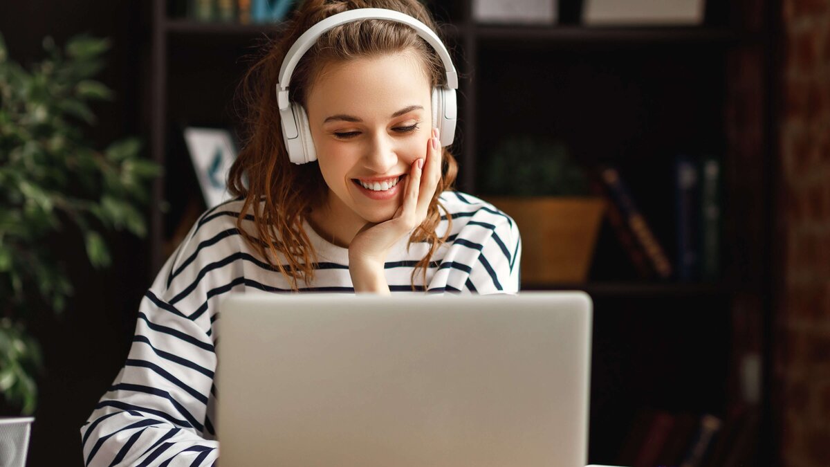 Frau mit Kopfhörern schaut auf Laptop