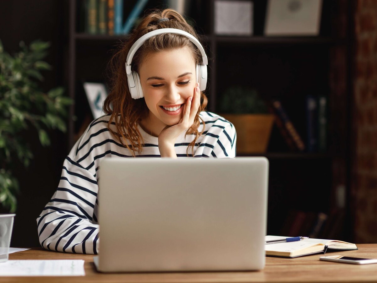 Frau mit Kopfhörern schaut auf Laptop
