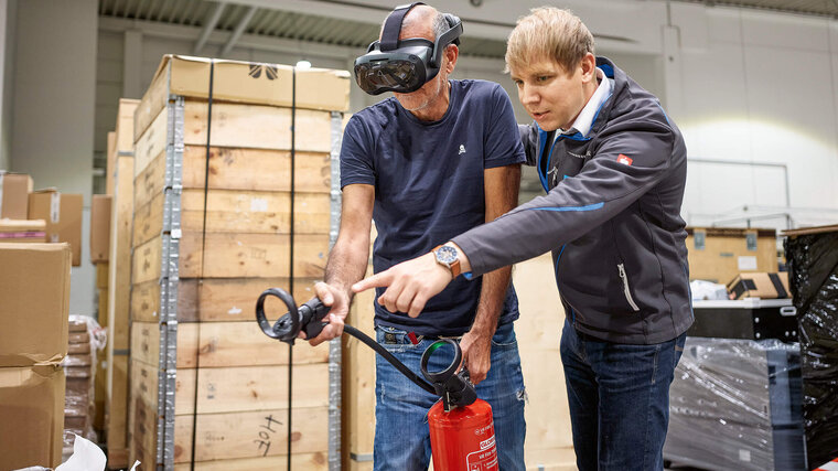 Brandschutzausbildung mit Virtuell Reality, zwei Personen üben mit einem Feuerlöscher einen simulierten Brand zu löschen