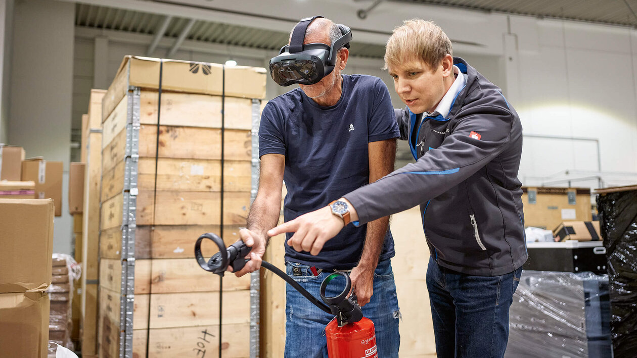 Brandschutzausbildung mit Virtuell Reality, zwei Personen üben mit einem Feuerlöscher einen simulierten Brand zu löschen