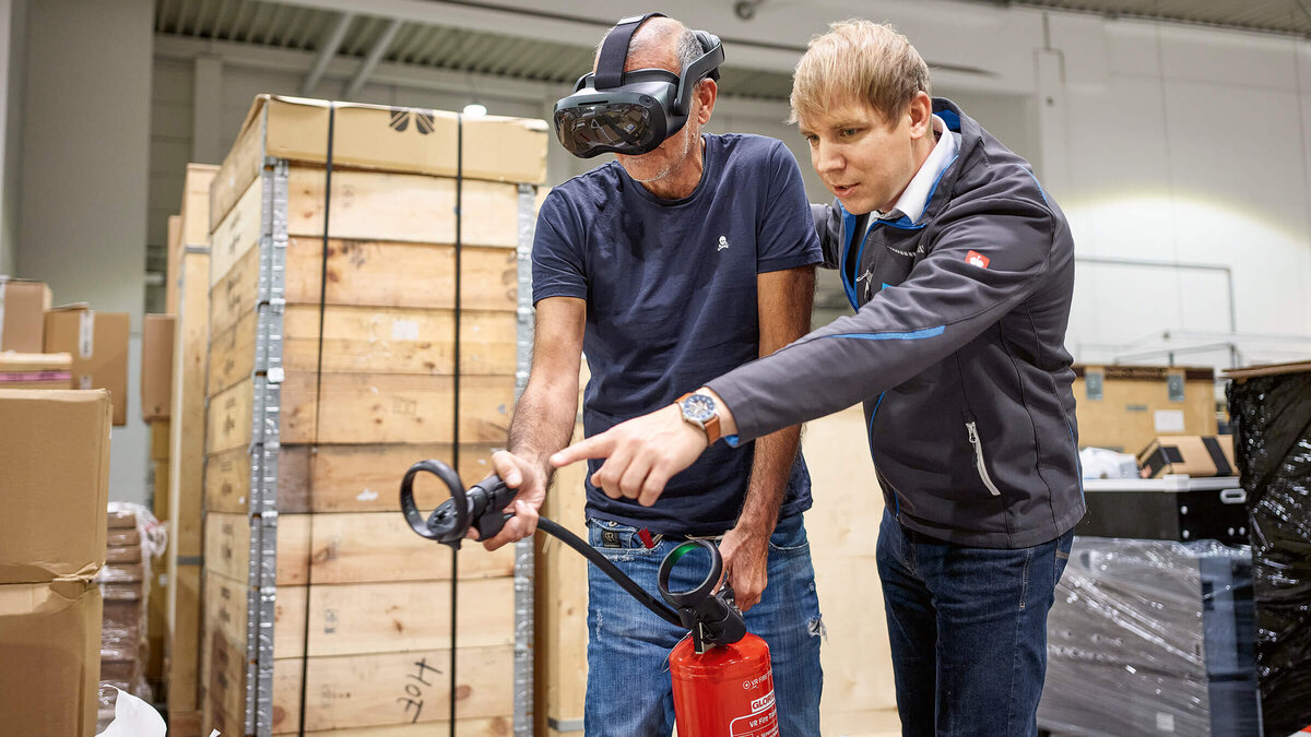 Brandschutzausbildung mit Virtuell Reality, zwei Personen üben mit einem Feuerlöscher einen simulierten Brand zu löschen