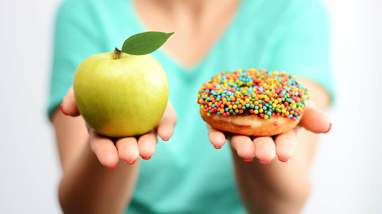 zur Wahl stehen ein Apfel und ein Donut mit bunten Streuseln