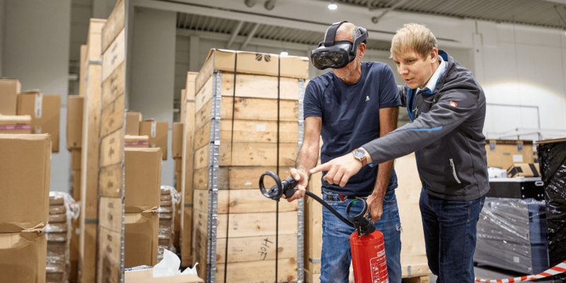 Brandschutzausbildung mit Virtuell Reality, zwei Personen üben mit einem Feuerlöscher einen simulierten Brand zu löschen