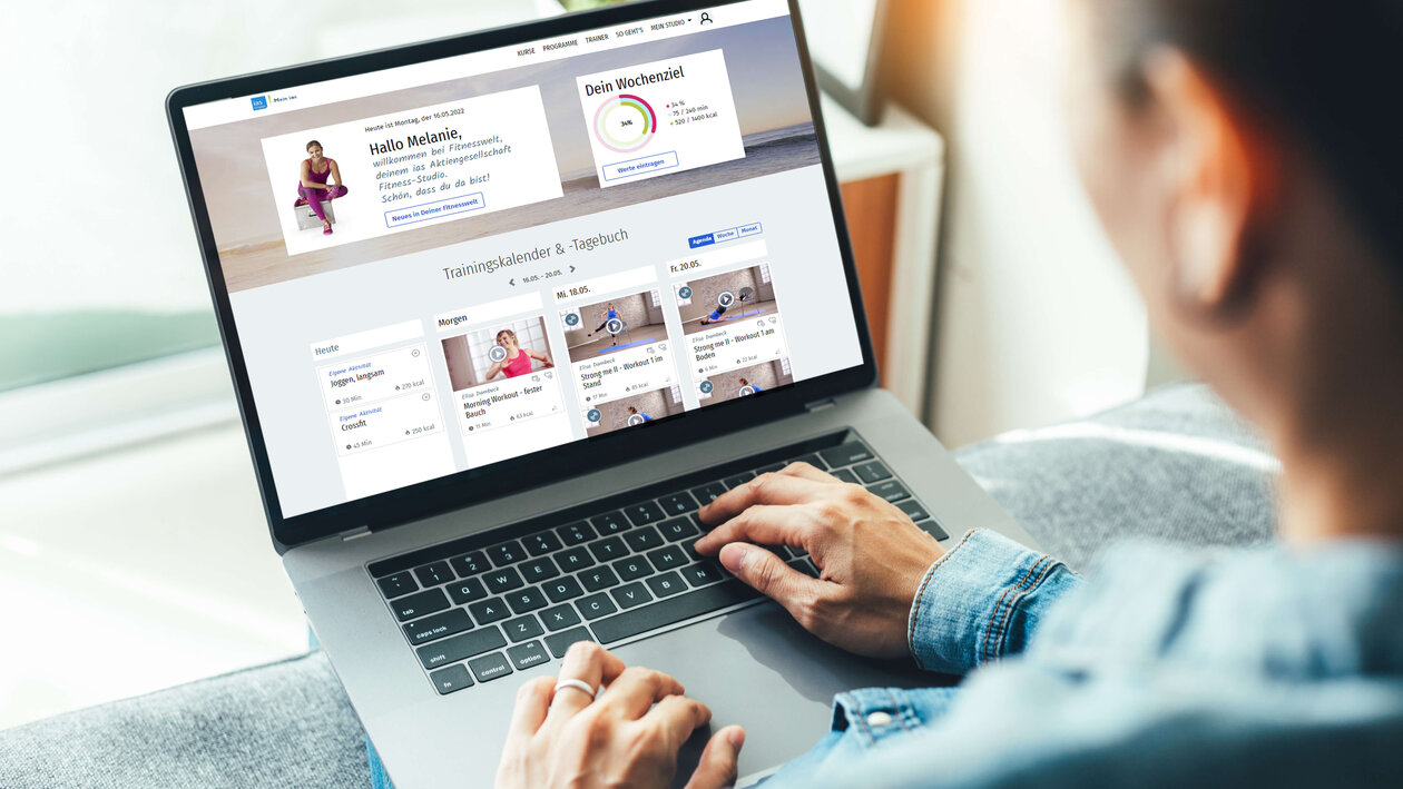 Frau am Laptop surft auf der Online-Fitnesswelt-Plattform