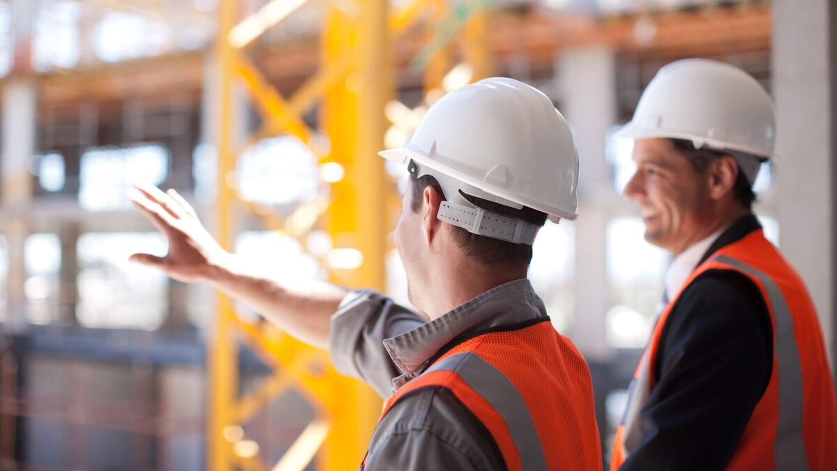 Bauarbeiter mit weißen Sicherheitshelmen und Warnwesten auf einer Baustelle