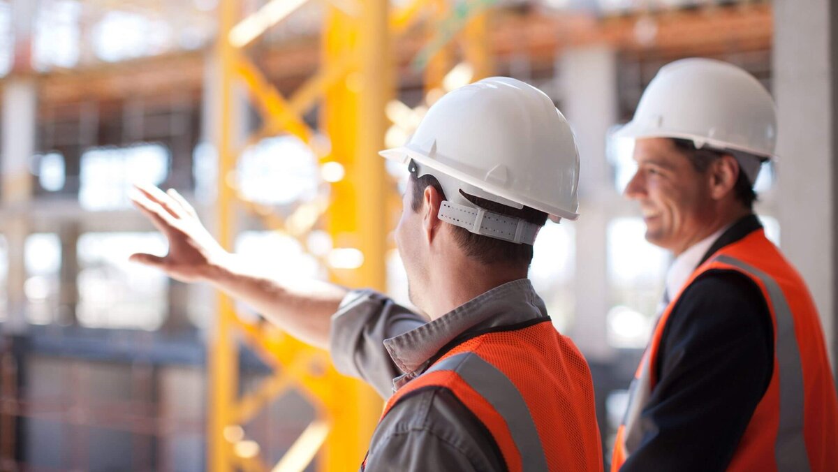 Bauarbeiter mit weißen Sicherheitshelmen und Warnwesten auf einer Baustelle