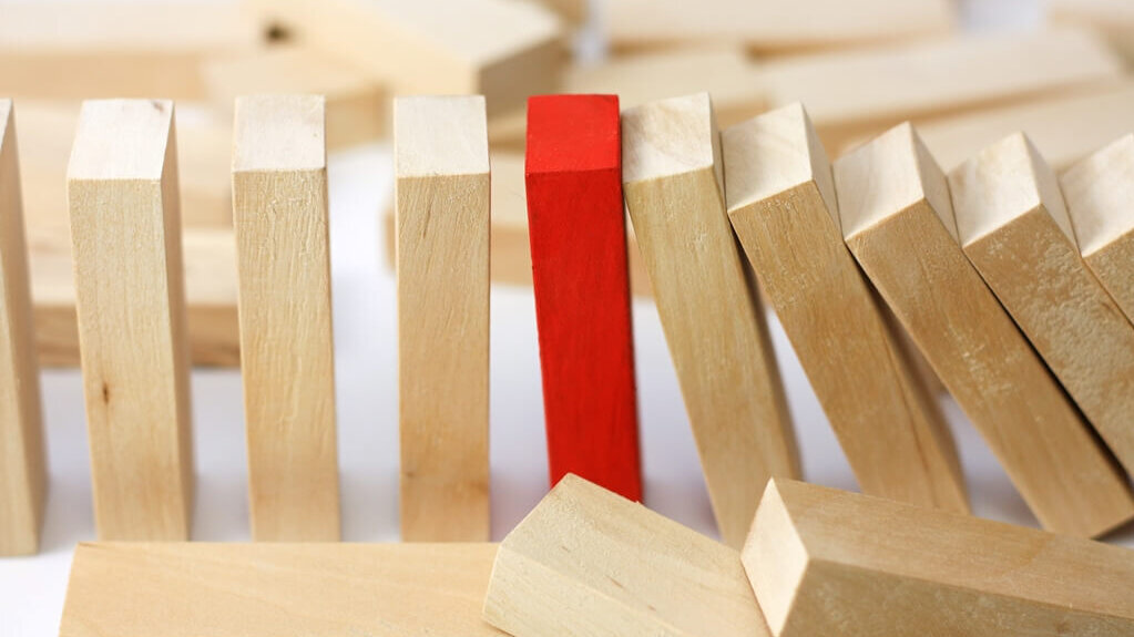 Reihe von aufgestellten Dominosteinen mit einem roten Stopper