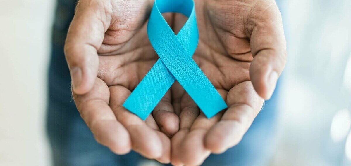 Blaue Schleife als Symbol für diverse Krankheiten in den Händen eines Mannes