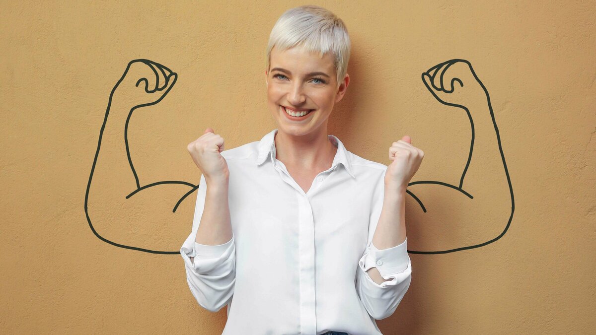 Immmunbooster Frau vor Wand mit großem Bizeps