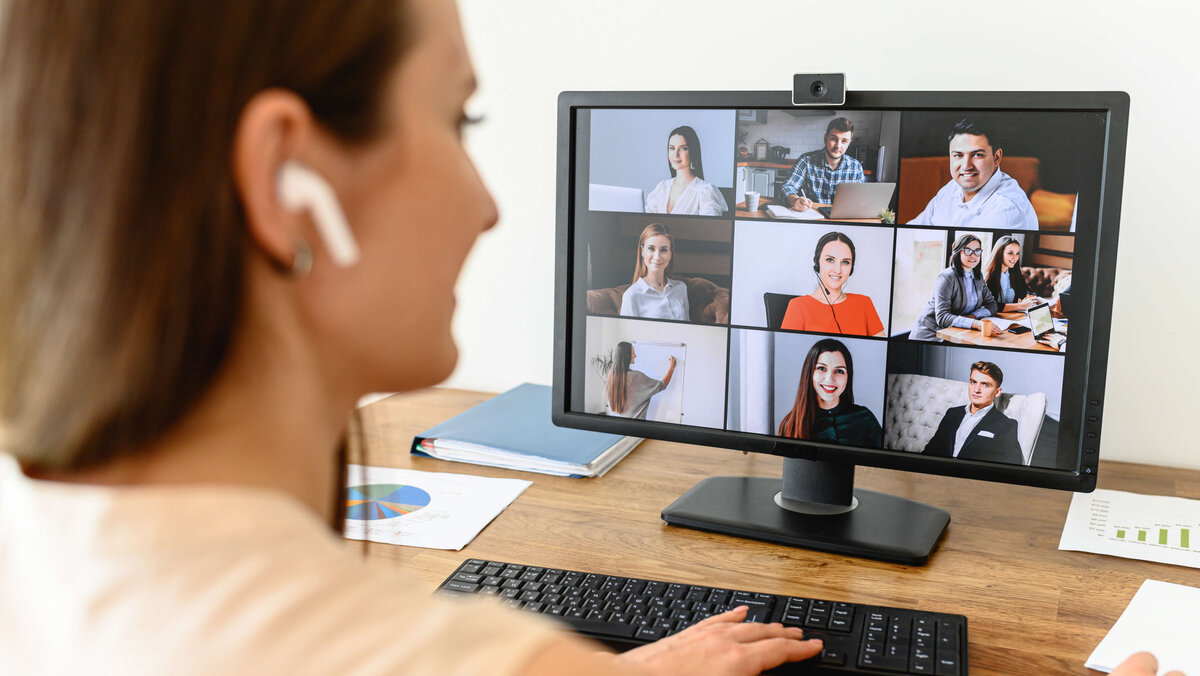 A woman connects with many employees via video looking at webcam
