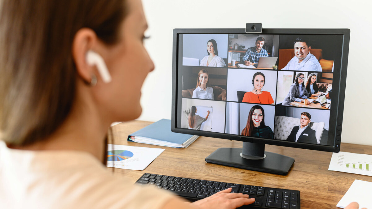 A woman connects with many employees via video looking at webcam