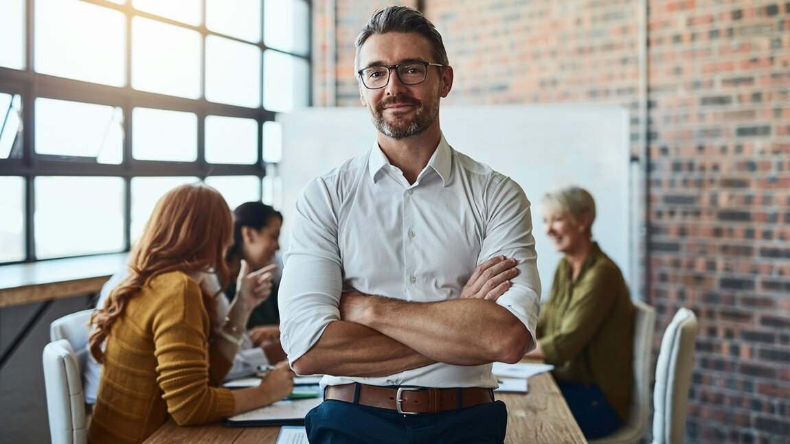 Mentale Gesundheit lächelnder Business-Mann mit verschränkten Armen im Besprechungsraum