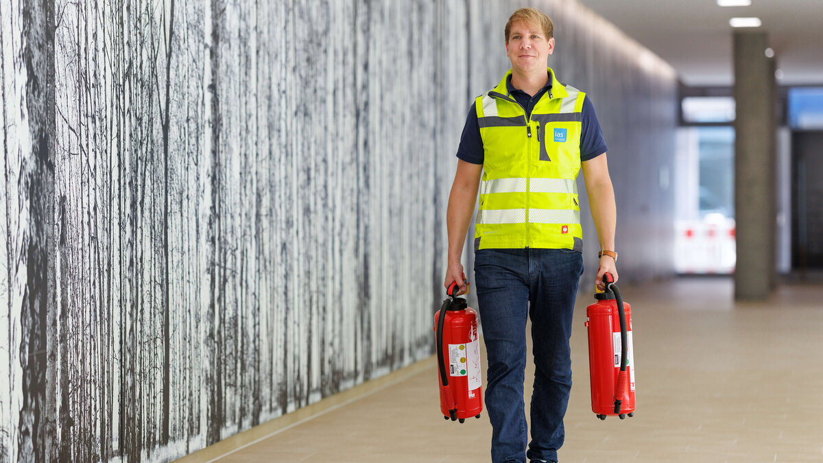 Sebastian Steder, Sicherheitsexperte der ias bei der Vorbereitung auf eine Brandschutzübung mit zwei Feuerlöschern