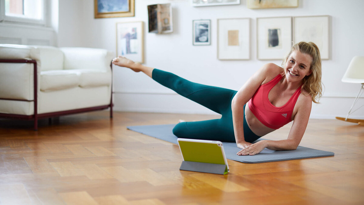 Mitarbeiter-Benefit Online-Fitness-Studio junge Frau beim Online-Home-Workout vor Laptop