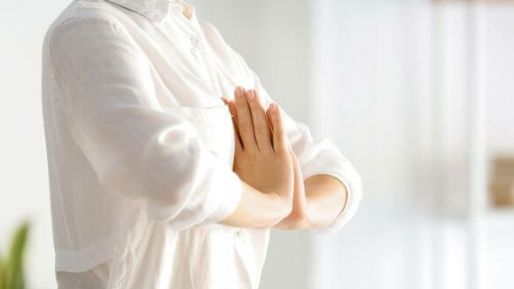 junge Frau in Yoga-Posa mit gefalteten Händen vor der Brust
